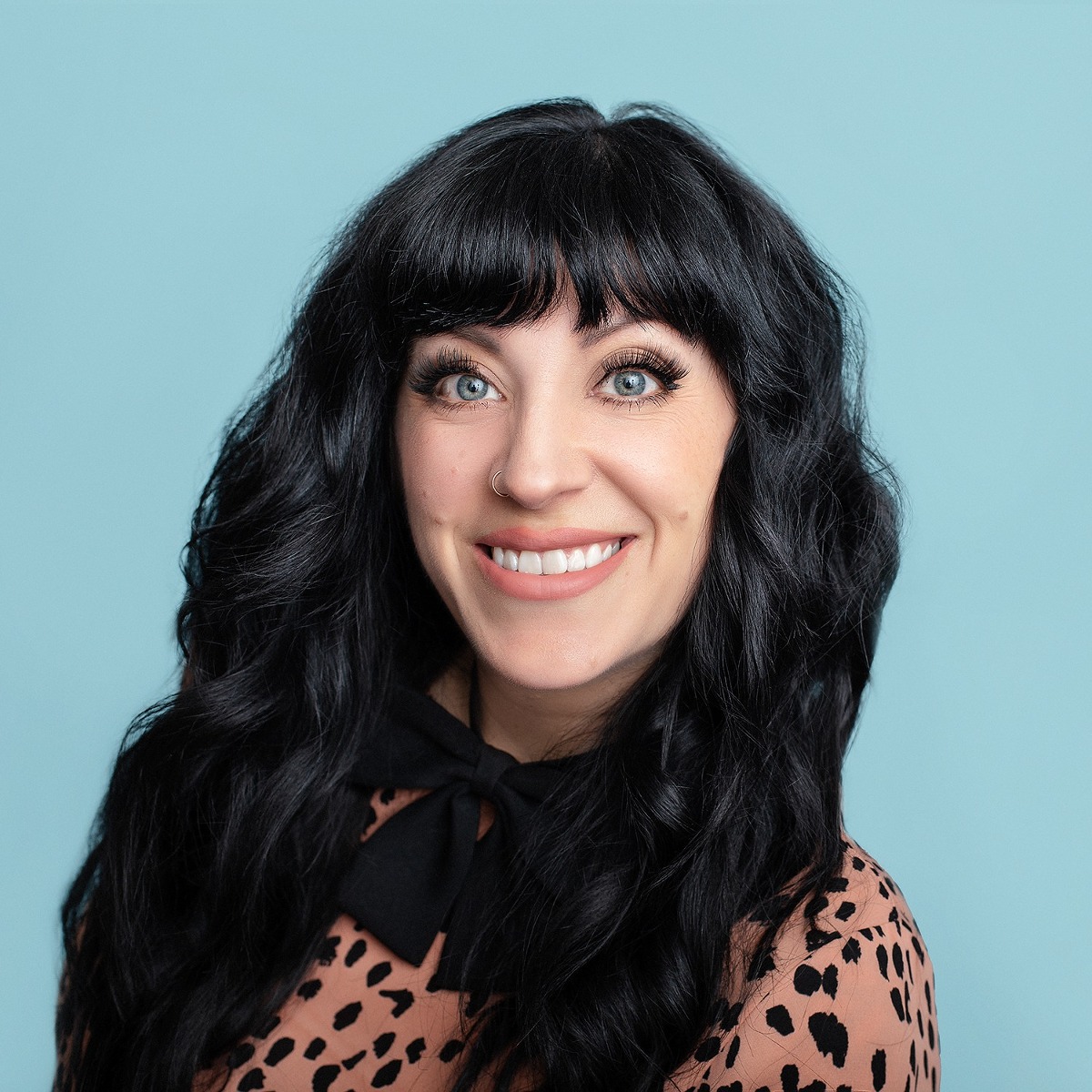 40 year old woman smiling for her headshot portrait in front of a blue background